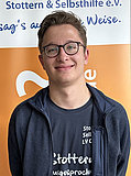 Einer von zwei Besitzern im Vorstand der BVSS ist Christoph Hassel. Klassisches Portraitfoto eines jungen Mannes mit Brille und kurzem Haar, er trägt ein schwarzes Polohemd