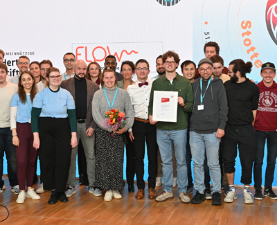 Junge Menschen mit Stottern engagieren sich bei Flow - Die junge Sprechgruppe der BVSS Eine Gruppe junger Menschen stehen auf einer Bühen zusammen, sie haben eine Urkunde erhalten, die sie zeigen.